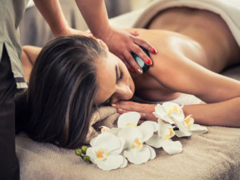 Woman receiving a massage with white flowers on a bed