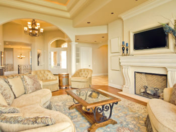 Luxurious living room with beige sofas, a coffee table, and a fireplace.