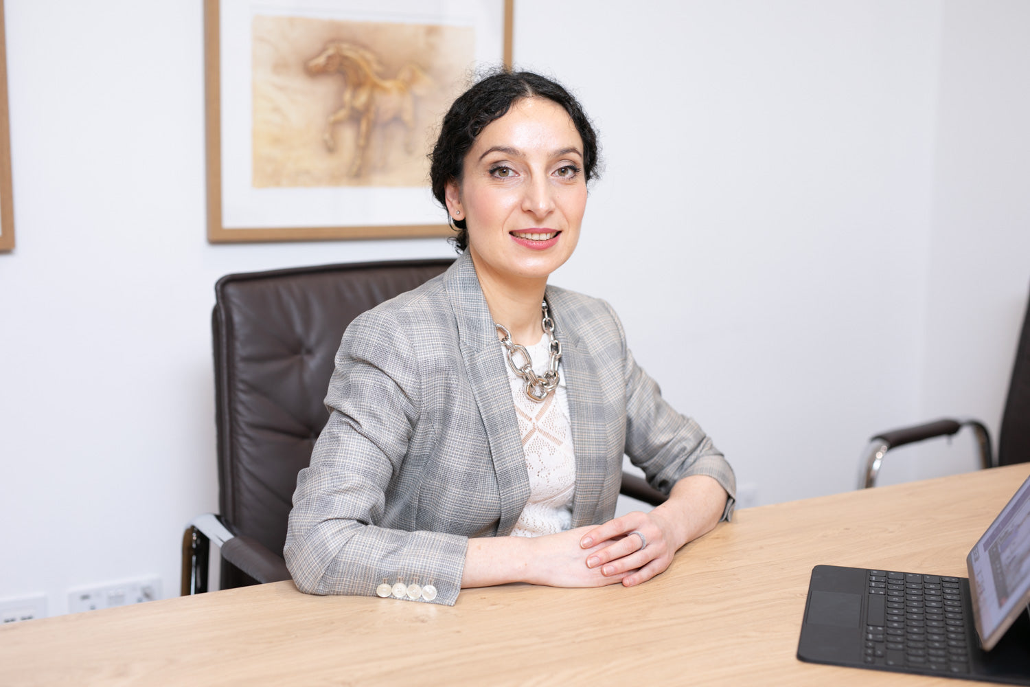 Woman sitting at a desk in an office setting with a laptop.