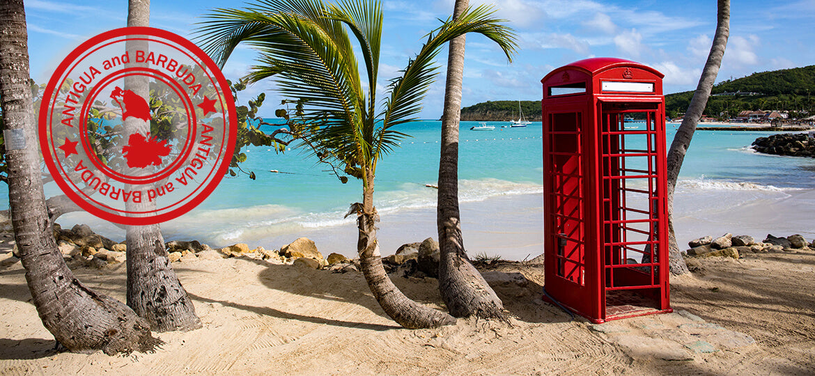 Red telephone booth on a tropical beach with palm trees and a clear blue sky.
