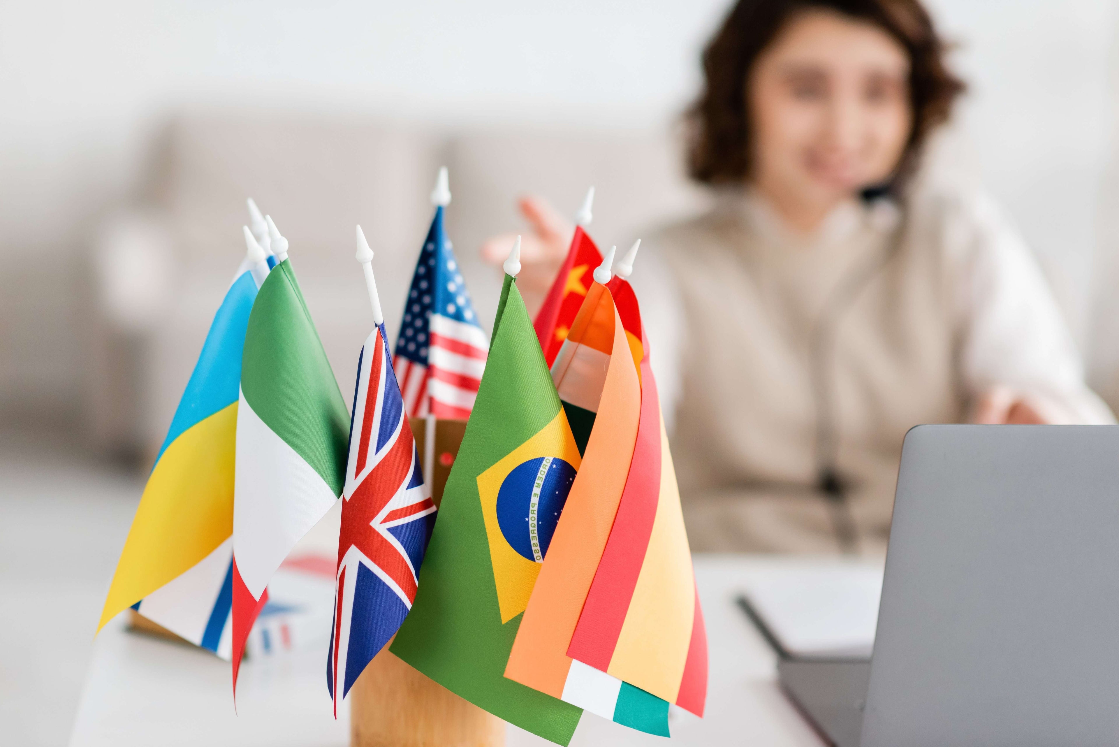 Person using a laptop with various national flags in the foreground