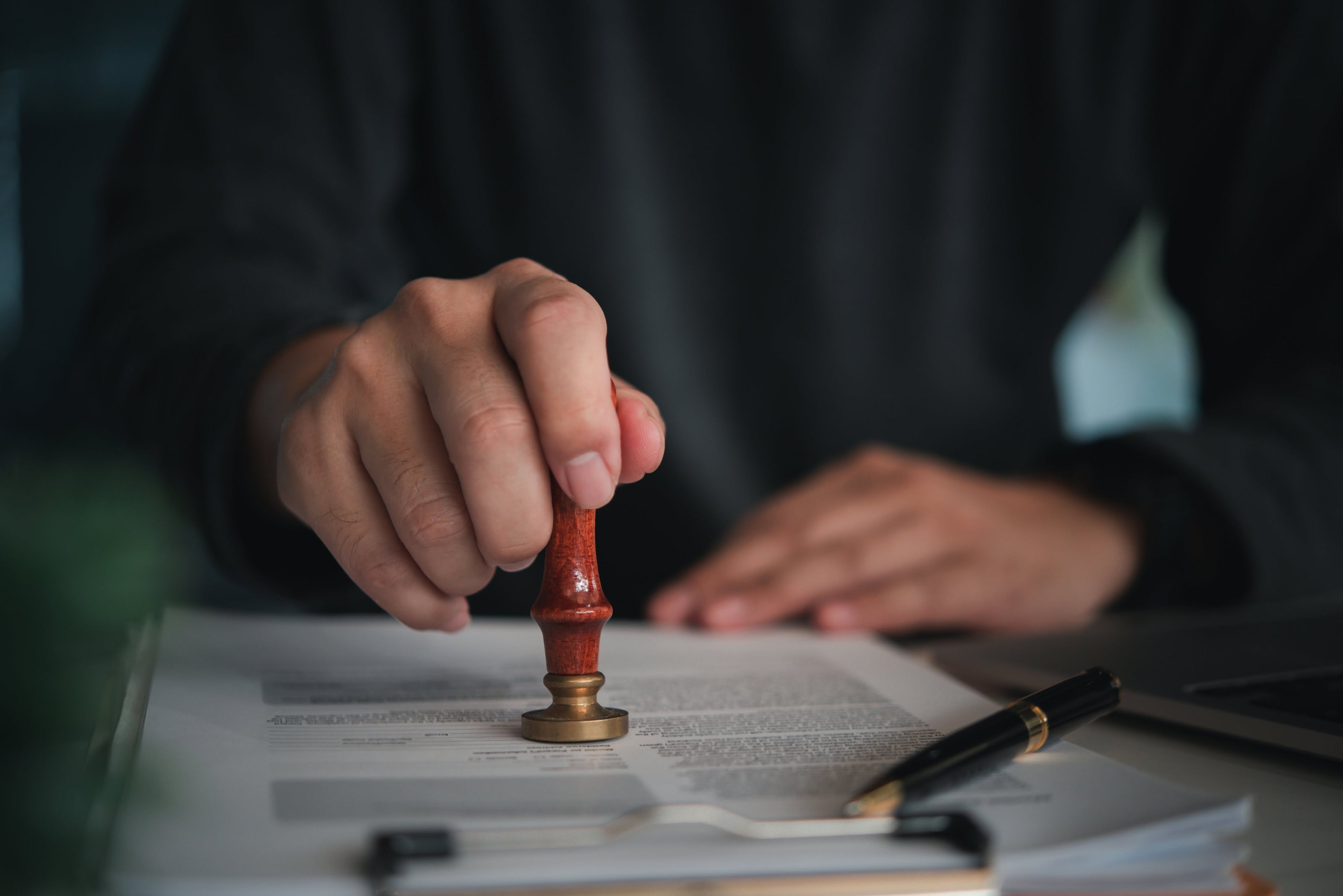 Hand placing a stamp on a document with a blurred background