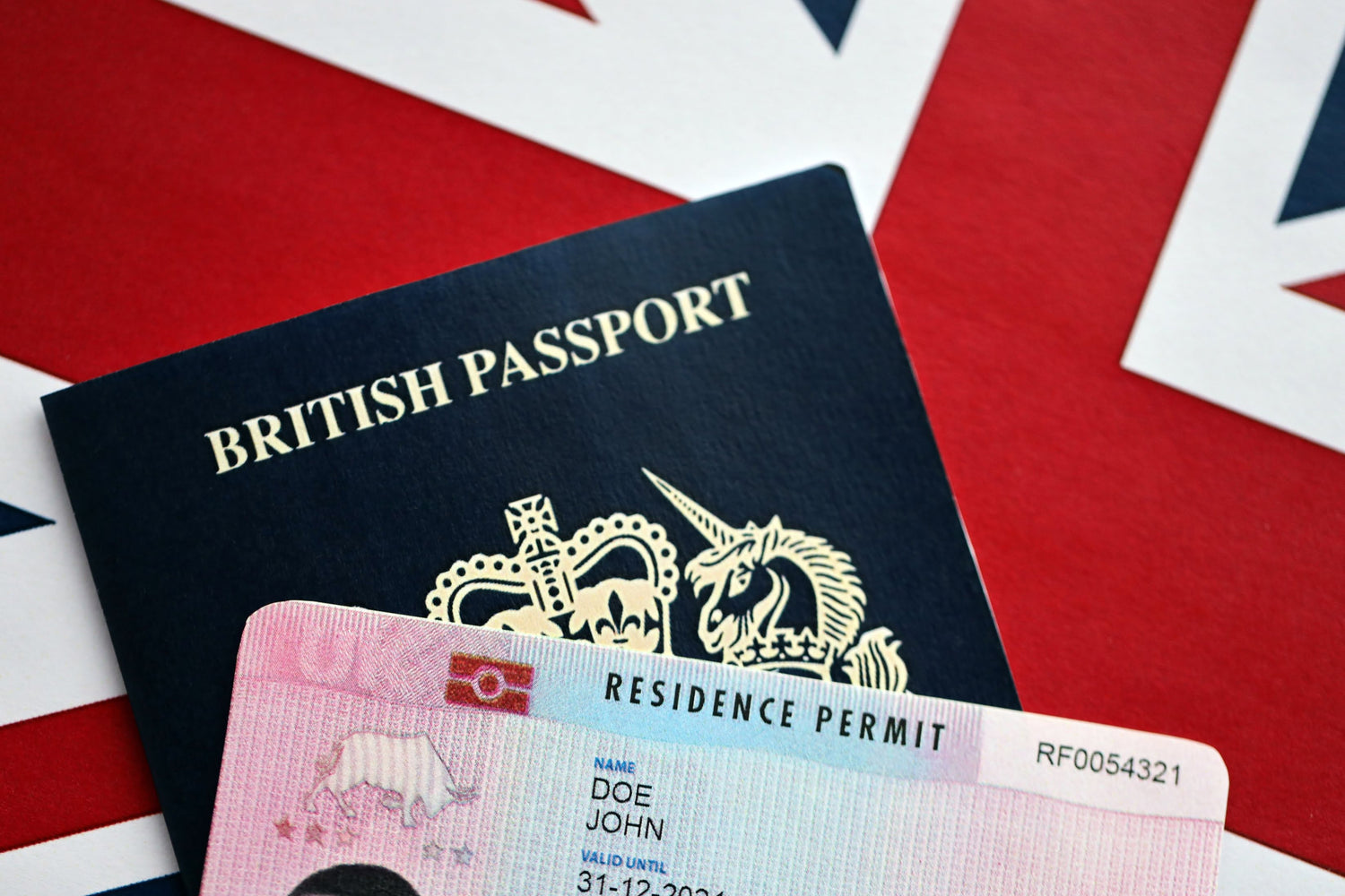 British passport and residence permit on a Union Jack flag background