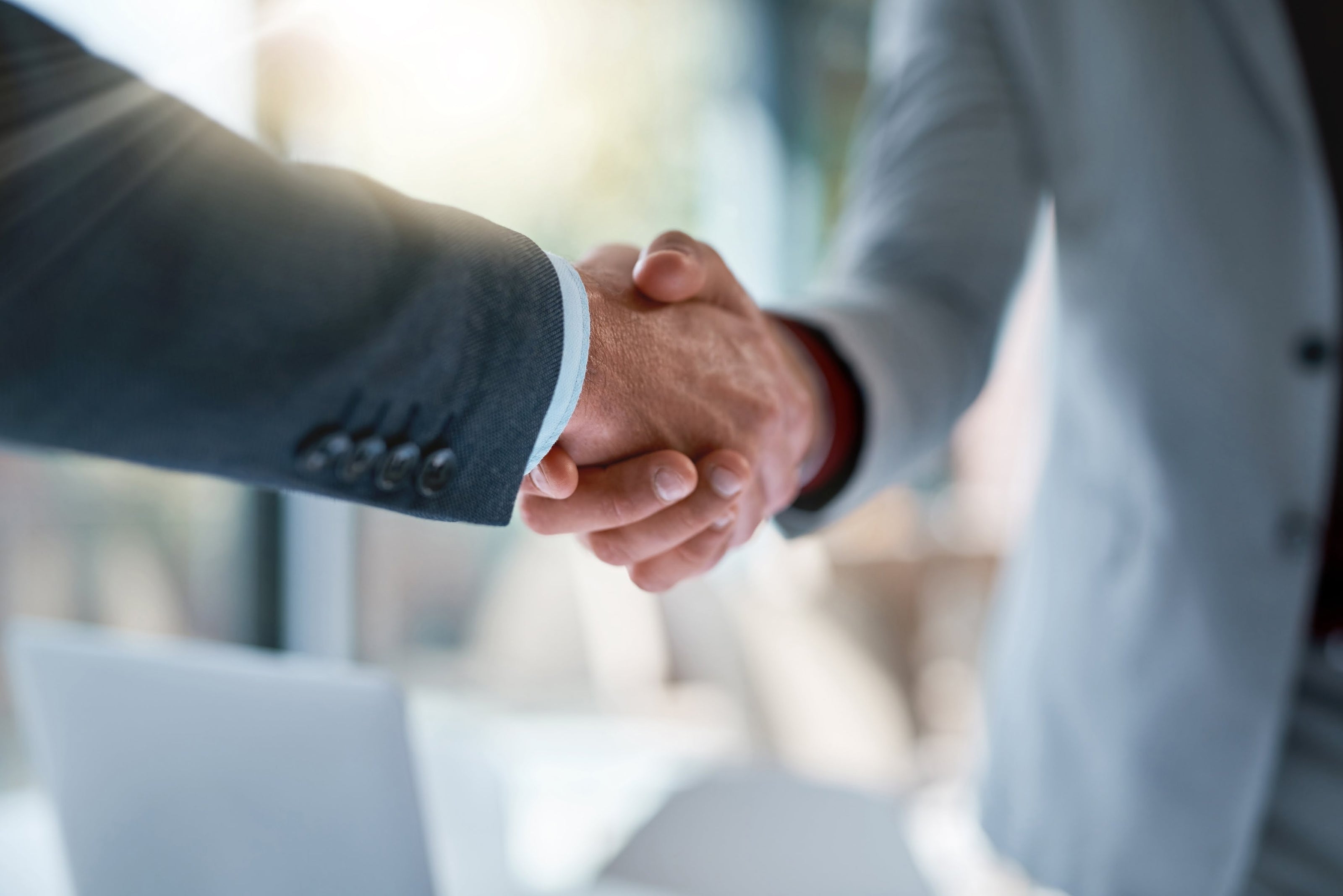 Two businesspeople shaking hands in an office setting