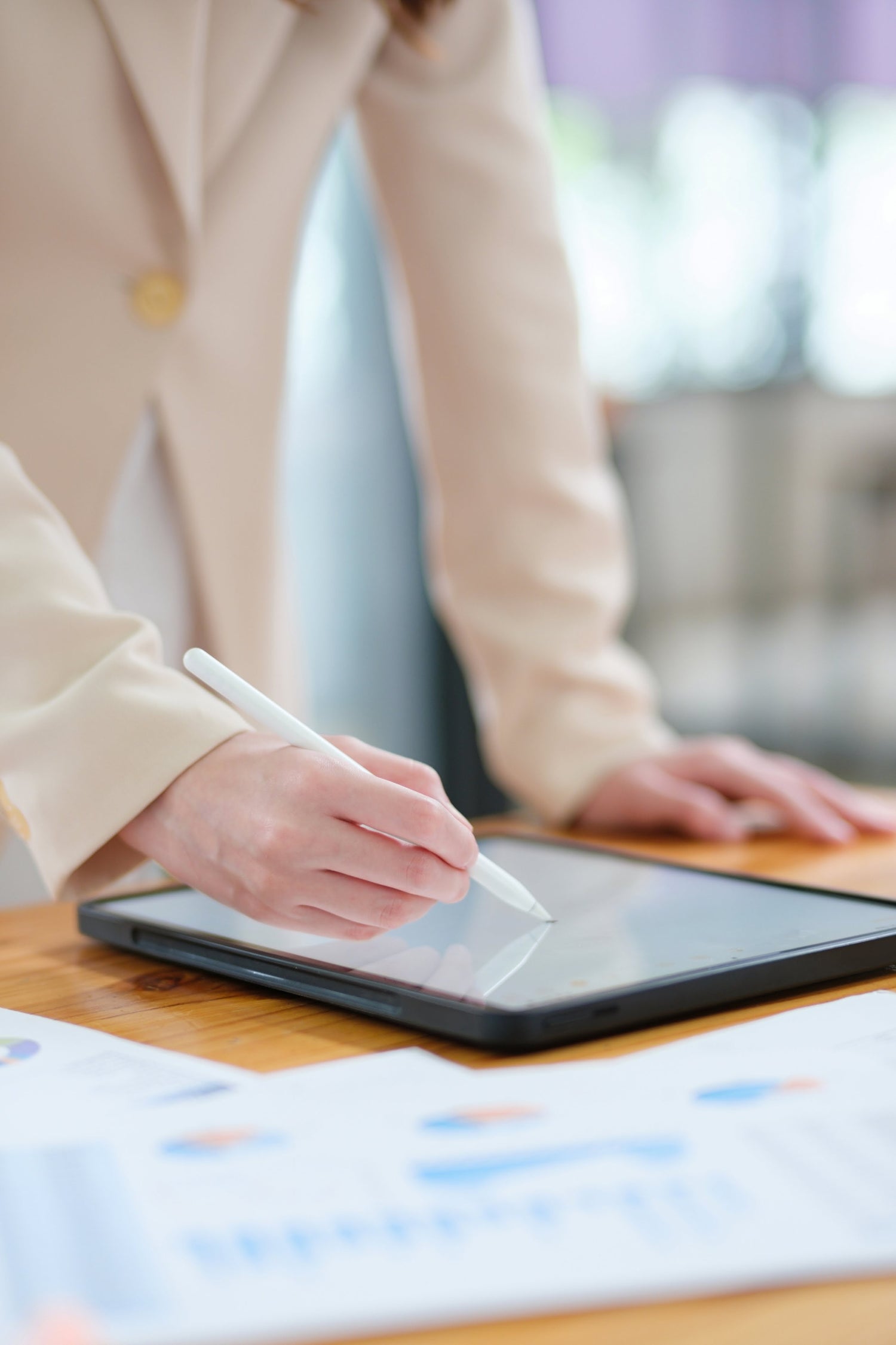 Person using a stylus on a tablet with a blurred office background