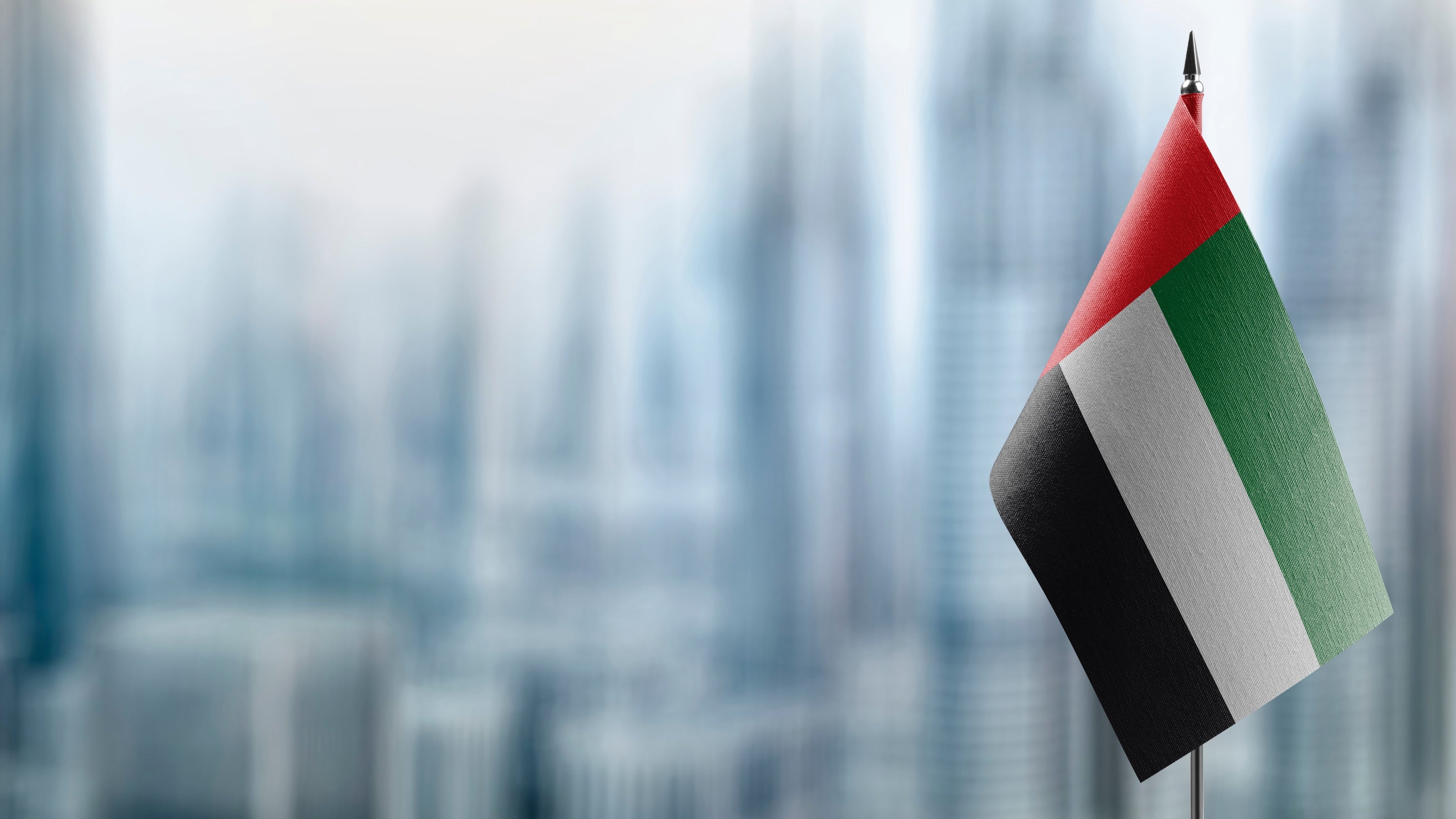 Flag of the United Arab Emirates against a blurred cityscape background