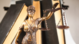 Statue of Lady Justice holding scales against a blurred background