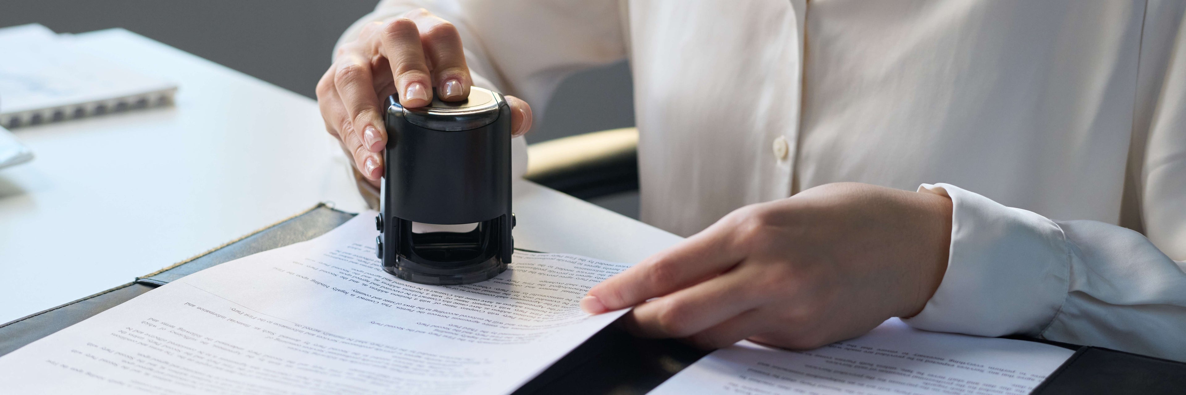 Person using a black stamp on documents with a blurred background