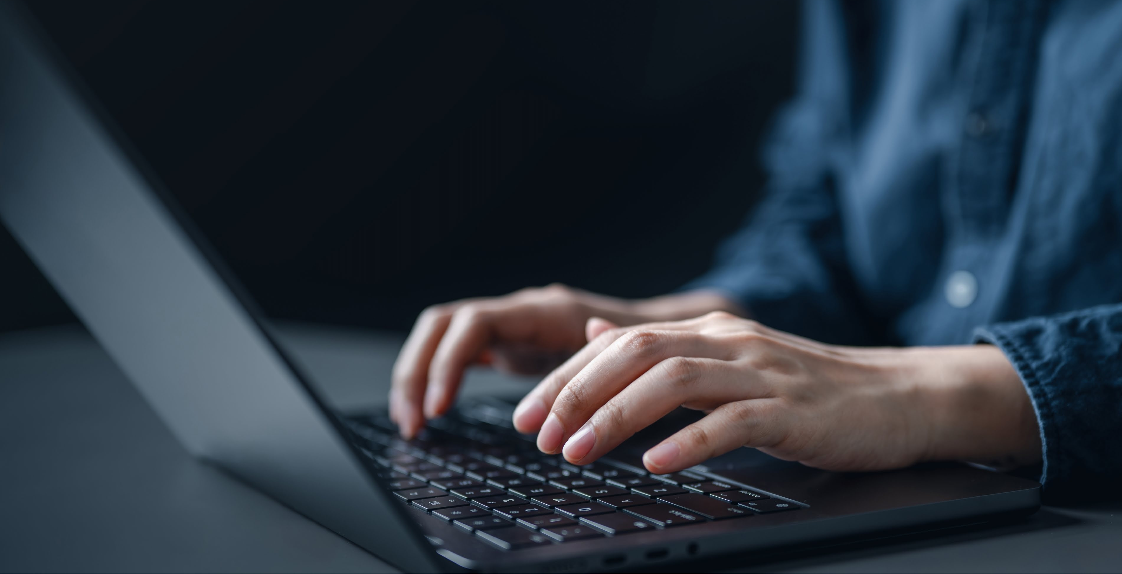 Close-up of hands typing on a laptop keyboard