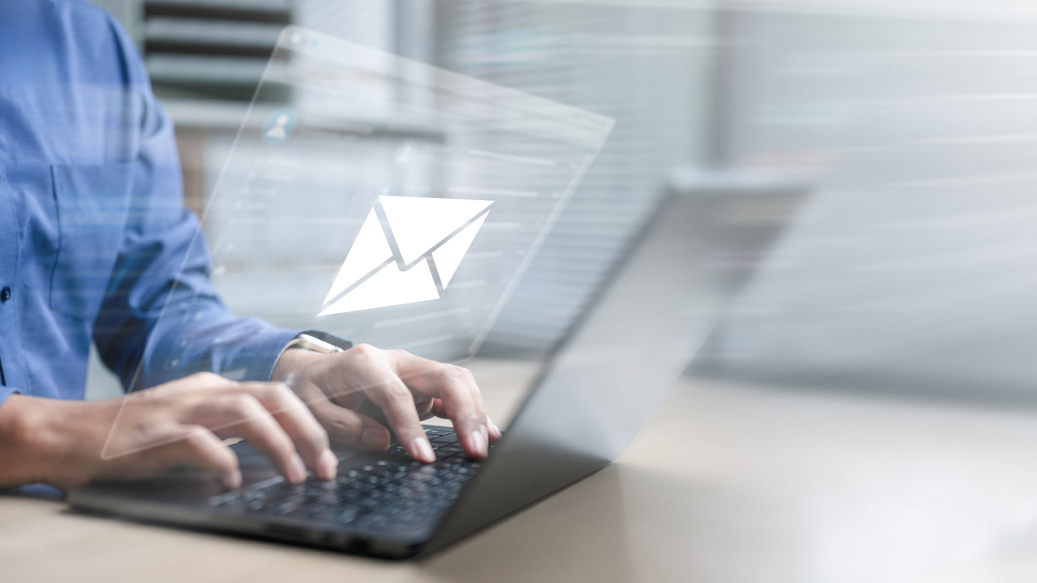 Person using a laptop with an envelope icon overlay, symbolizing email.