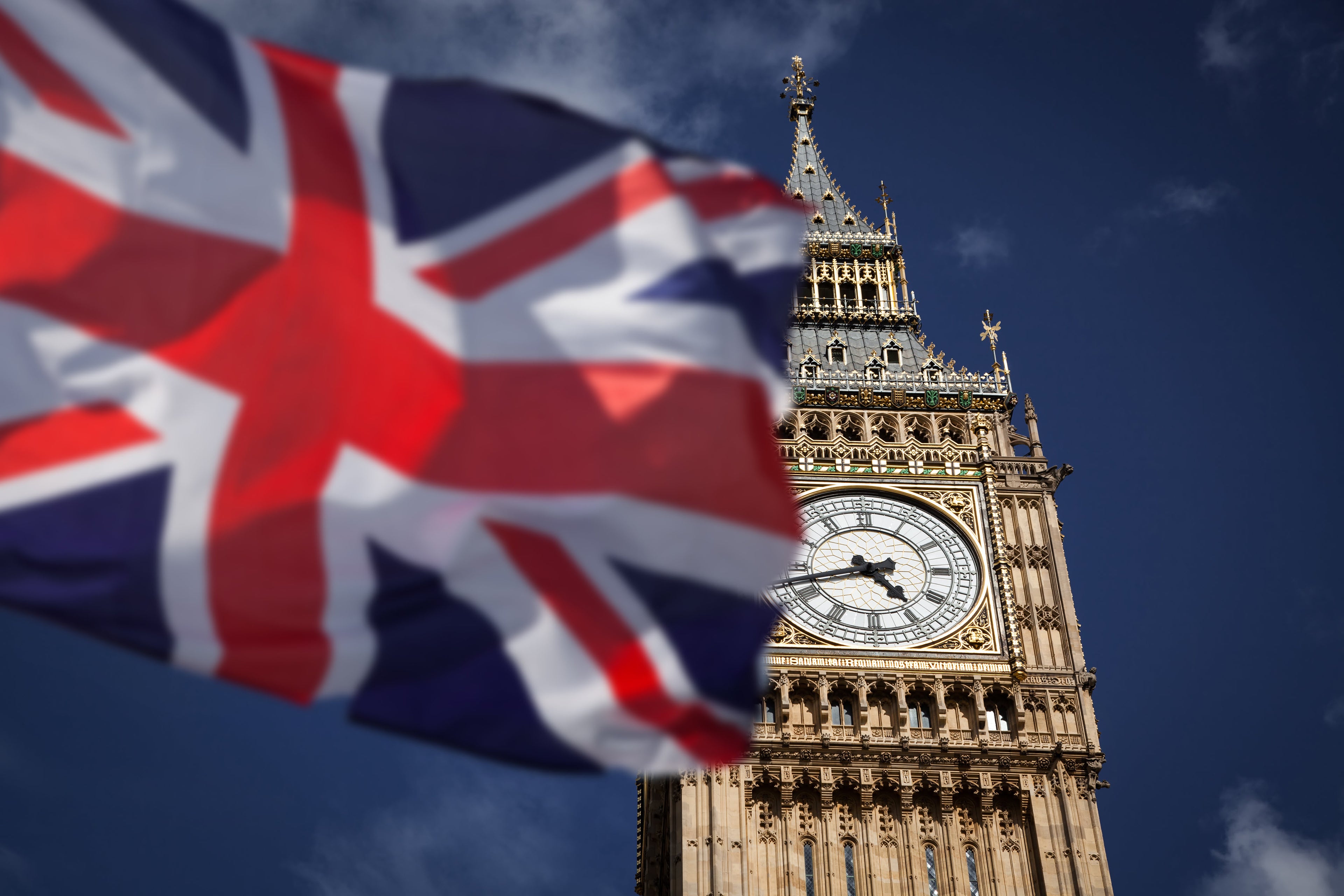 Union Jack flag waving in front of Big Ben against a blue sky